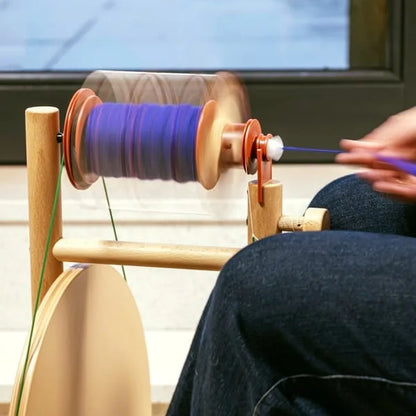 Nahaufnahme des Lojan Buddy Doppeltritt Spinnrads beim Spinnen von lila Garn, laufende Spule mit ruhigem Einzug und ergonomischer Handführung